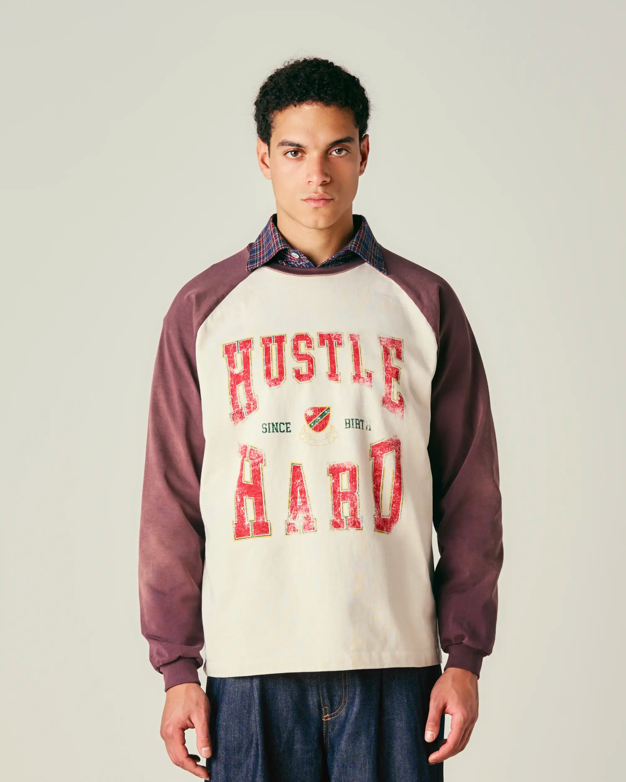 Person wearing a sweatshirt with 'Hustle Hard' text on a plain background