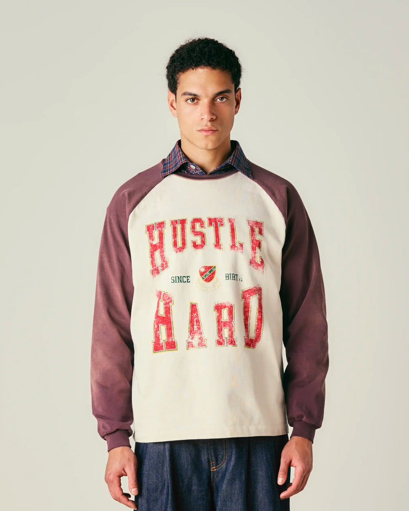 Person wearing a sweatshirt with 'Hustle Hard' text on a plain background