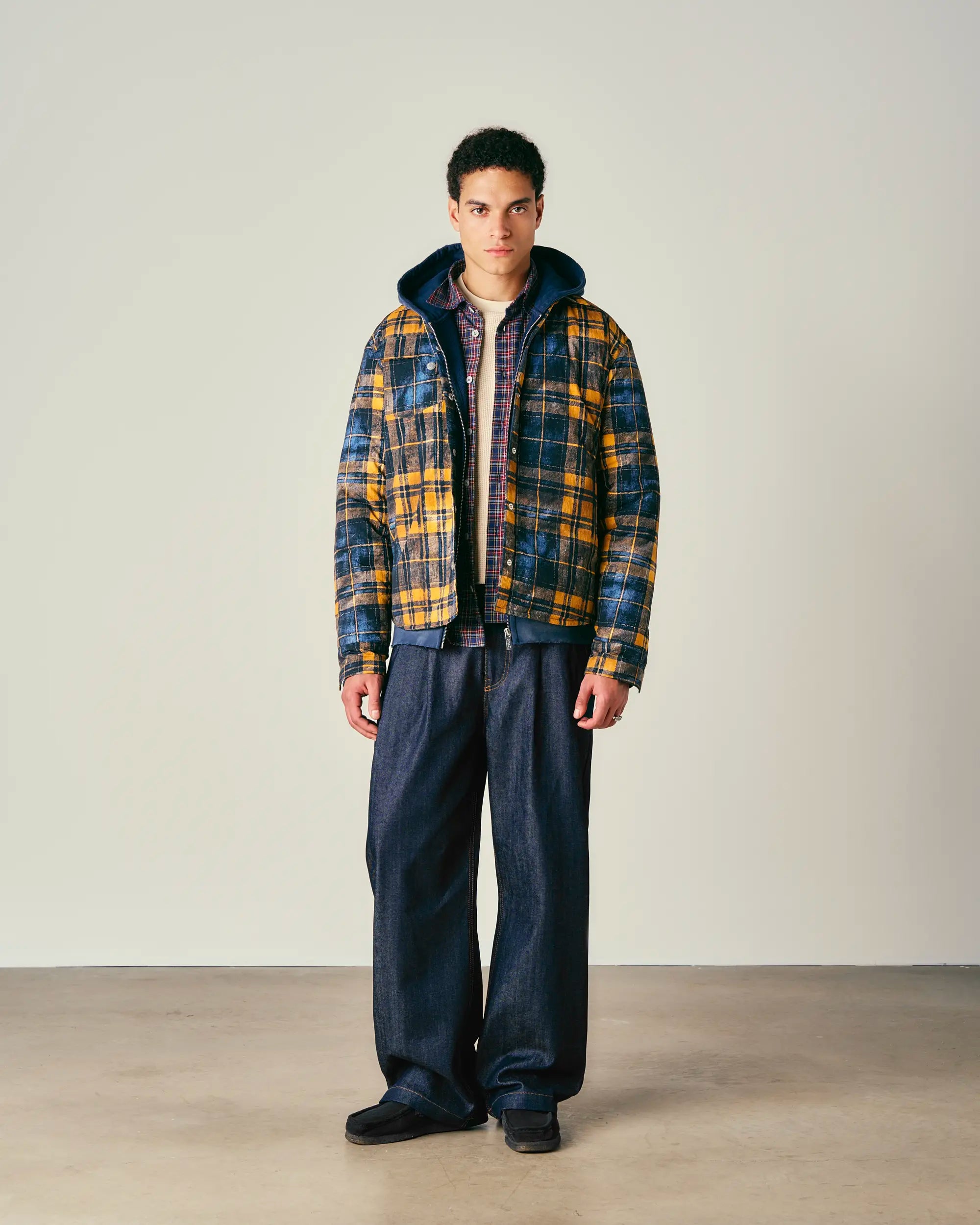 Man wearing a padded jacket and dark pants on a plain background