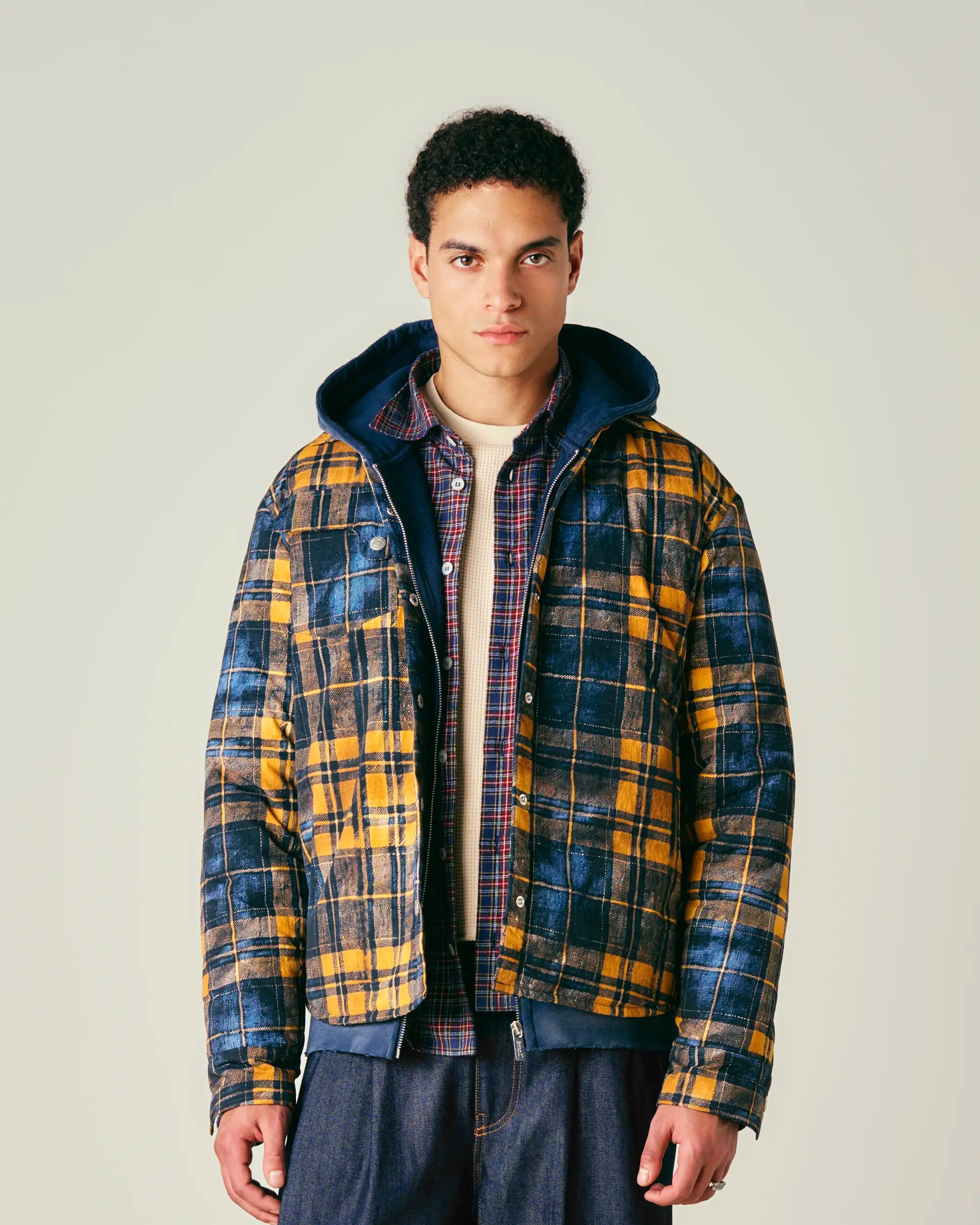 Man wearing a padded jacket with a hood on a plain background